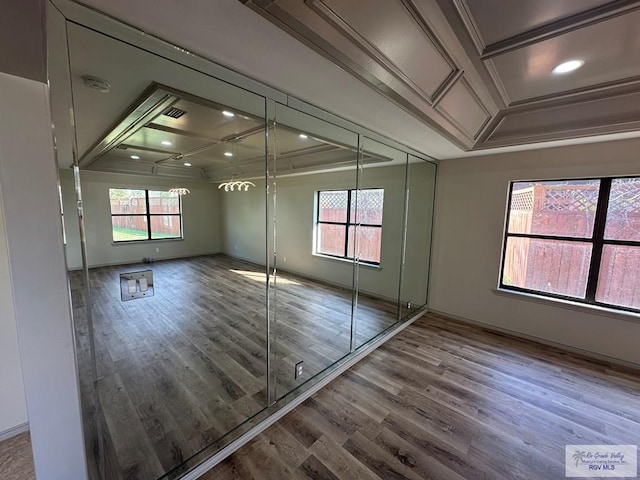 interior space featuring crown molding, coffered ceiling, and hardwood / wood-style flooring