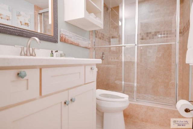 bathroom featuring tile patterned floors, vanity, a shower with shower door, and toilet