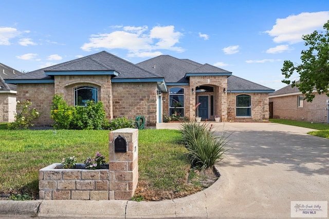 1730 Christian Cir, Harlingen, TX 78550 - french country home featuring a front lawn, concrete driveway, stone siding, and brick siding