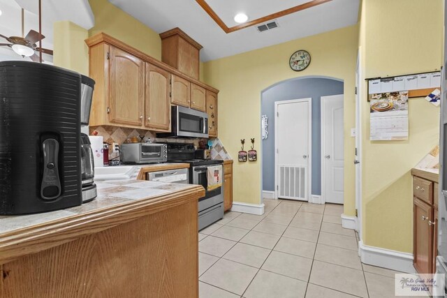 1730 Christian Cir, Harlingen, TX 78550 - kitchen featuring appliances with stainless steel finishes, arched walkways, decorative backsplash, light tile patterned floors, and tile countertops