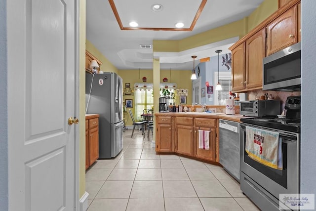1730 Christian Cir, Harlingen, TX 78550 - kitchen featuring stainless steel appliances, brown cabinets, light tile patterned floors, hanging light fixtures, and recessed lighting