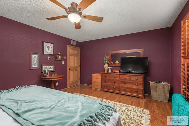 bedroom featuring hardwood / wood-style flooring, ceiling fan, and a textured ceiling