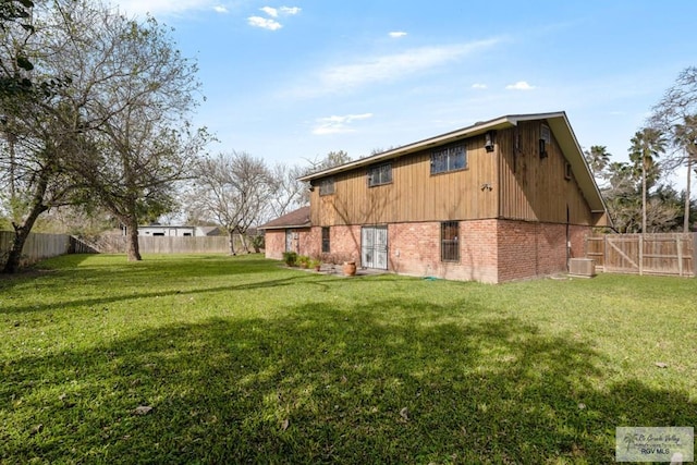 back of property with central AC unit and a yard