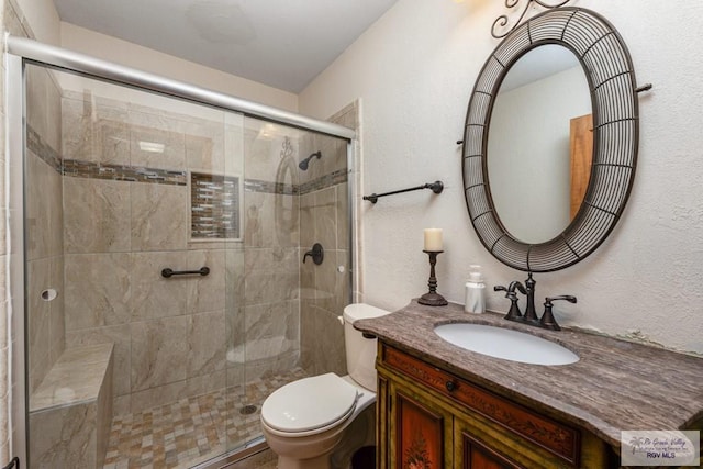 bathroom featuring vanity, a shower with shower door, and toilet