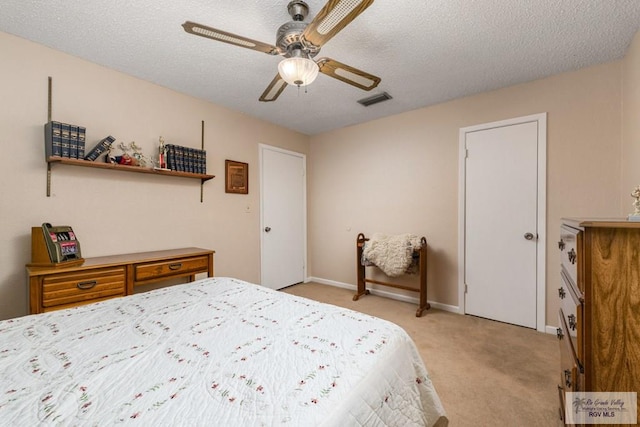 bedroom featuring ceiling fan, light colored carpet, and a textured ceiling