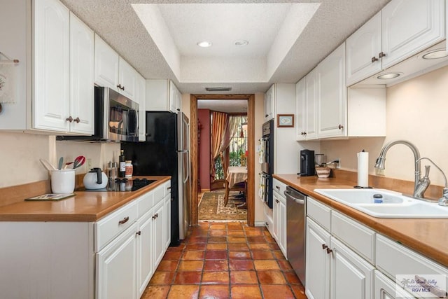 kitchen with black appliances, a raised ceiling, sink, and white cabinets