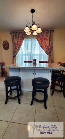 tiled dining room with a notable chandelier