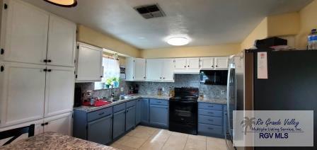 kitchen featuring gray cabinets, white cabinetry, black appliances, and decorative backsplash