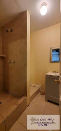 bathroom with tile patterned flooring, sink, and tiled shower