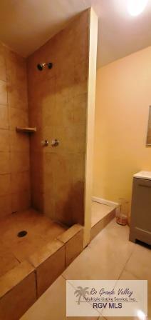 bathroom with tile patterned flooring and tiled shower