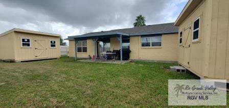 rear view of house with a yard, a storage unit, and a patio area