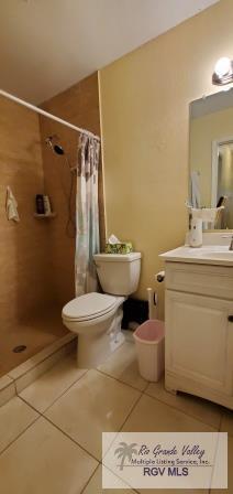 bathroom featuring toilet, a shower with curtain, vanity, and tile patterned floors