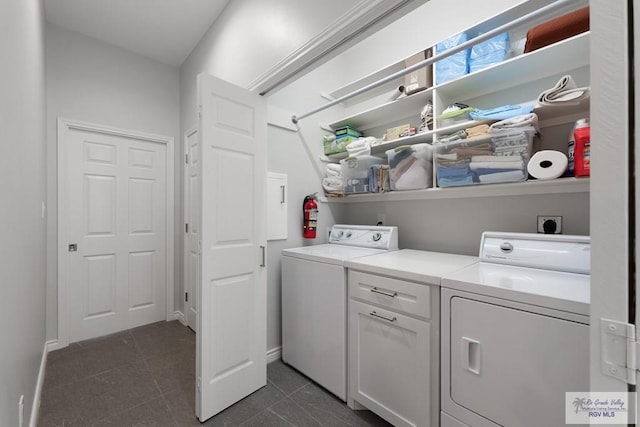 clothes washing area with washer and dryer, laundry area, dark tile patterned floors, and baseboards