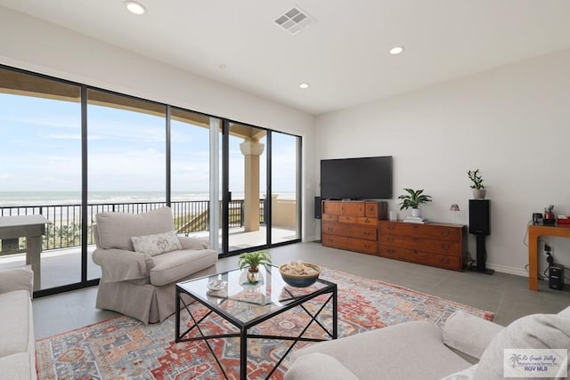 tiled living room featuring a water view, baseboards, visible vents, and recessed lighting