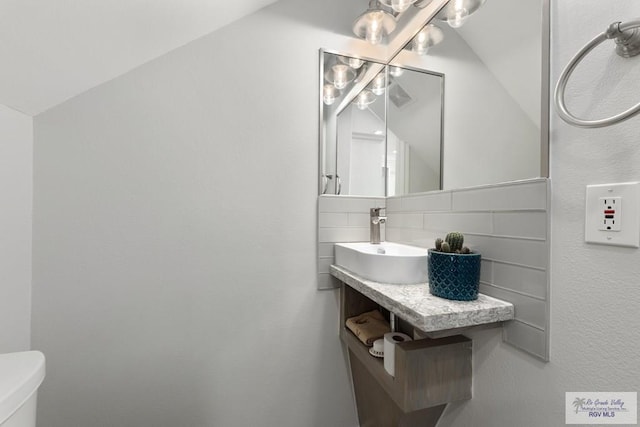 half bathroom featuring tasteful backsplash, vanity, and toilet