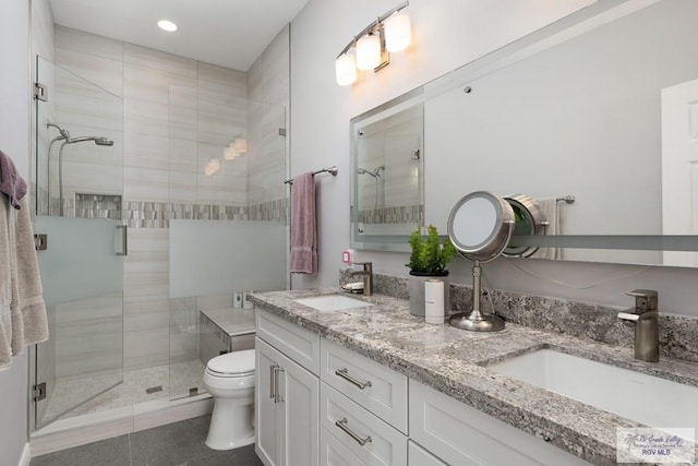 full bathroom featuring double vanity, a sink, toilet, and a shower stall