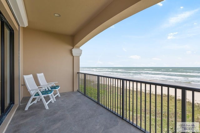 balcony featuring a water view and a beach view