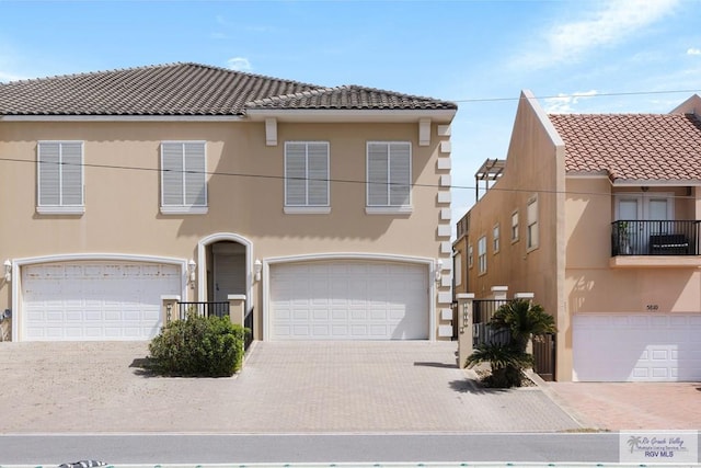 view of front of house with a garage, driveway, a tiled roof, and stucco siding