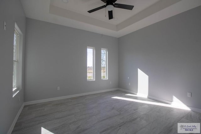 spare room featuring baseboards, a raised ceiling, and a ceiling fan