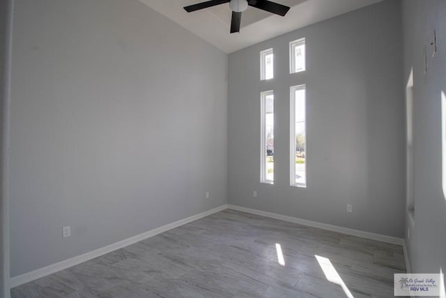 empty room with ceiling fan, plenty of natural light, and baseboards