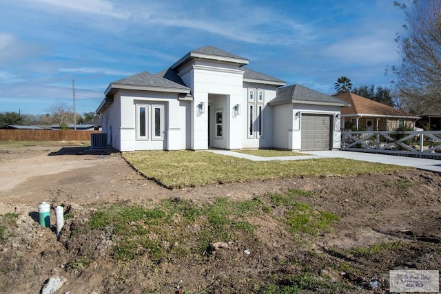 prairie-style home with stucco siding, an attached garage, central AC unit, fence, and driveway