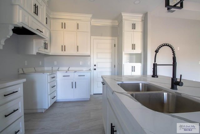 kitchen with crown molding, visible vents, white cabinetry, a sink, and light stone countertops