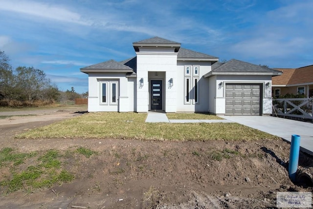 prairie-style house with concrete driveway, an attached garage, fence, a front yard, and stucco siding