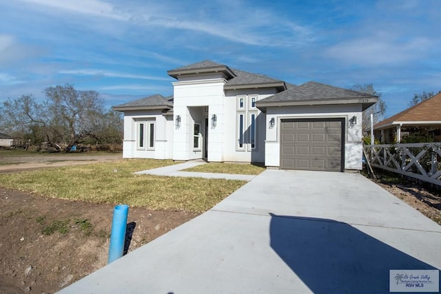 prairie-style home featuring a garage, driveway, a front lawn, and stucco siding