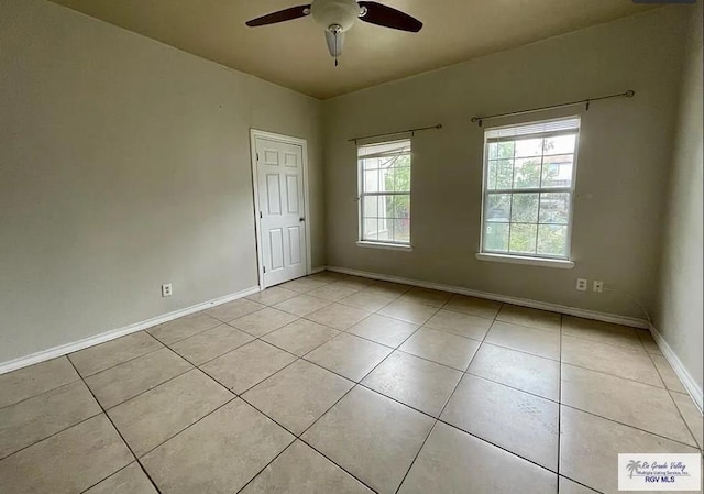 spare room with ceiling fan, light tile patterned flooring, and baseboards