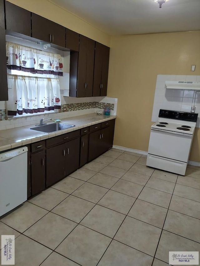 kitchen with tile countertops, light tile patterned floors, white appliances, a sink, and decorative backsplash