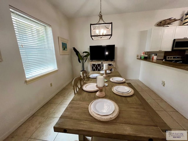 dining area featuring baseboards, an inviting chandelier, and light tile patterned floors