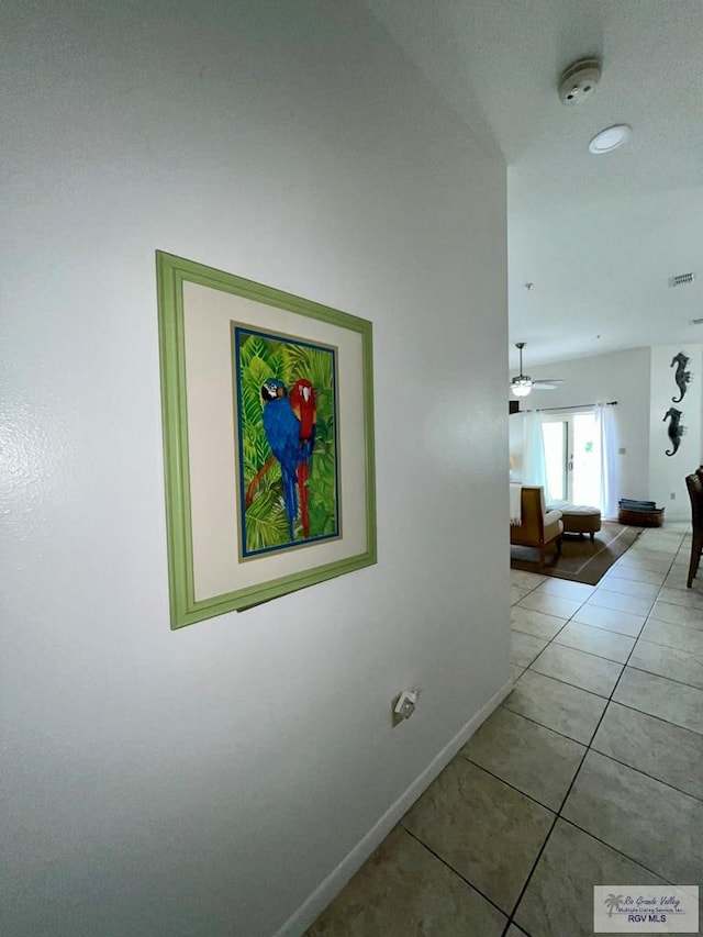 hall featuring tile patterned floors, baseboards, and visible vents
