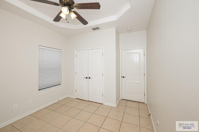 1508 W 20th St, Mission, TX 78572 - unfurnished bedroom with light tile patterned flooring, a tray ceiling, a closet, baseboards, and a ceiling fan