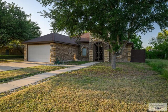 1508 W 20th St, Mission, TX 78572 - view of front of house with concrete driveway, a front yard, an attached garage, and stone siding