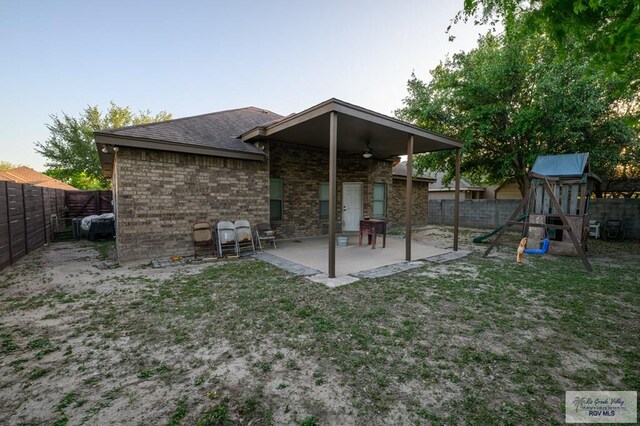1508 W 20th St, Mission, TX 78572 - rear view of house with ceiling fan, a patio, a fenced backyard, a playground, and brick siding