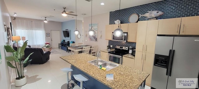 kitchen featuring sink, a kitchen island with sink, decorative light fixtures, decorative backsplash, and appliances with stainless steel finishes