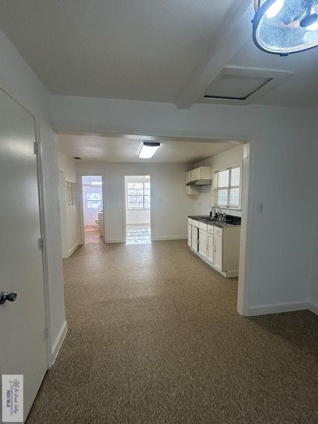 unfurnished living room with beamed ceiling and sink