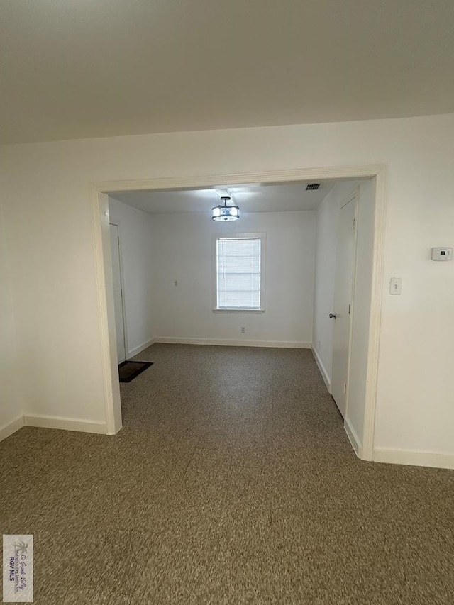 unfurnished room featuring dark colored carpet