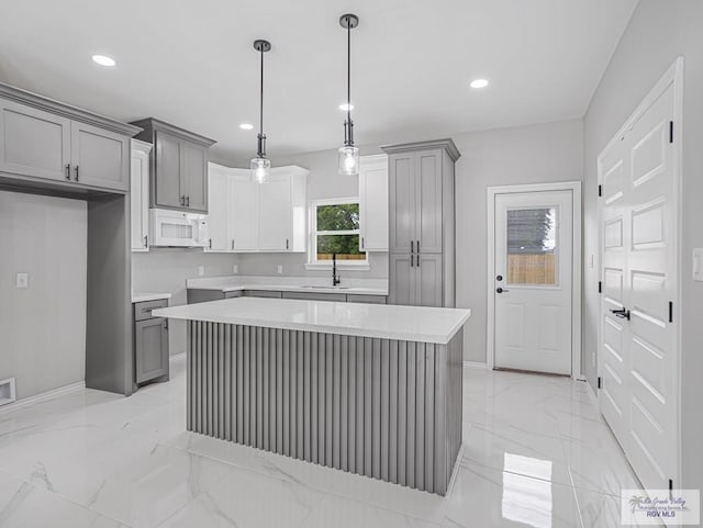 kitchen with a kitchen island, sink, and gray cabinetry