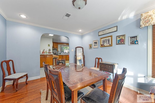 dining room with light hardwood / wood-style flooring and crown molding