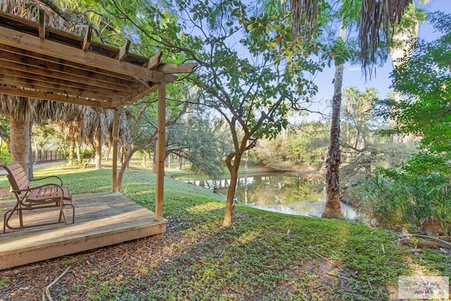 view of yard with a deck with water view and a pergola