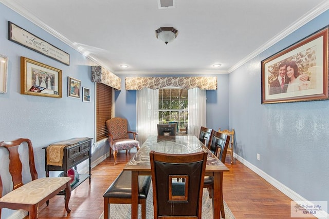 dining space with hardwood / wood-style floors and ornamental molding