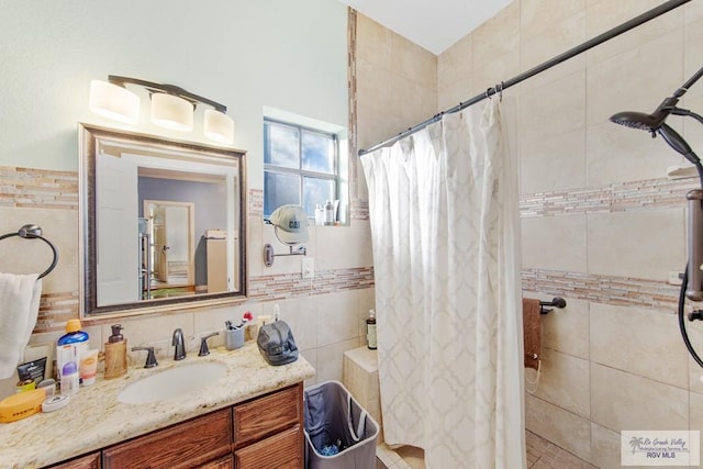 bathroom featuring a shower with curtain, vanity, and tile walls