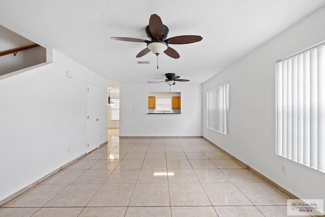 unfurnished living room featuring plenty of natural light, ceiling fan, and light tile patterned floors