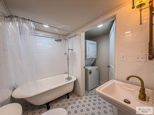 1214 W Lincoln Ave Unit 22, Harlingen, TX 78550 - bathroom with stacked washer / drying machine, a sink, toilet, tile walls, and a combined bath / shower with freestanding tub