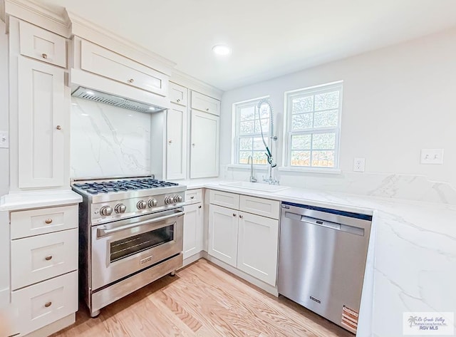 1214 W Lincoln Ave Unit 22, Harlingen, TX 78550 - kitchen featuring appliances with stainless steel finishes, a sink, light stone counters, light wood-type flooring, and white cabinetry