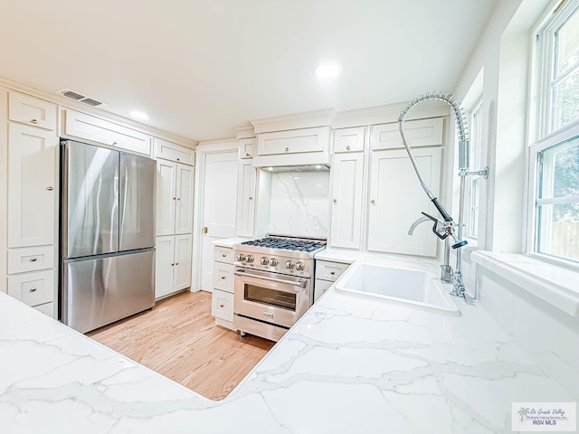 1214 W Lincoln Ave Unit 22, Harlingen, TX 78550 - kitchen featuring stainless steel appliances, a sink, white cabinets, light stone countertops, and under cabinet range hood
