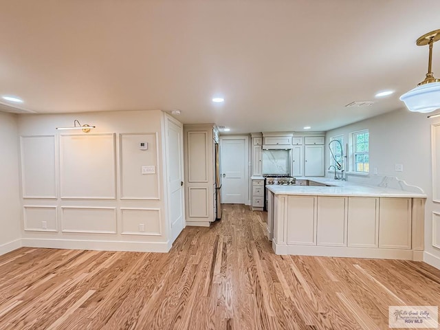 1214 W Lincoln Ave Unit 22, Harlingen, TX 78550 - kitchen featuring light countertops, light wood finished floors, a peninsula, a sink, and hanging light fixtures