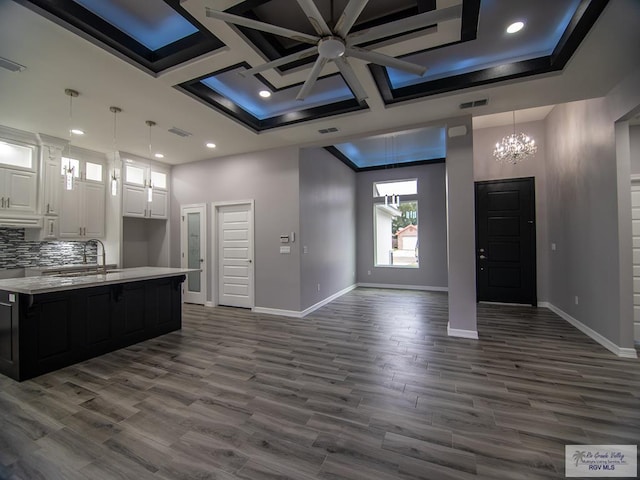 kitchen with light countertops, open floor plan, a sink, coffered ceiling, and baseboards