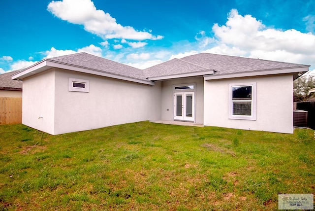 back of property with a shingled roof, a lawn, fence, french doors, and stucco siding